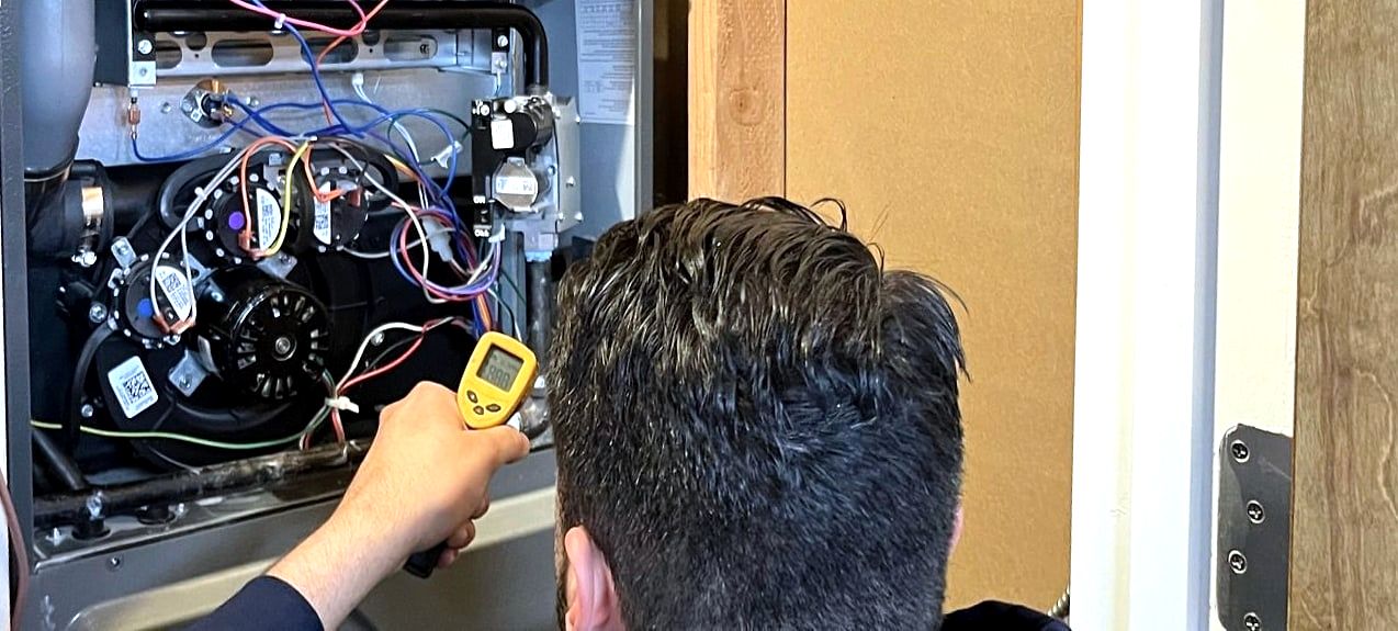 Technician using infrared thermometer on open furnace, seen from behind